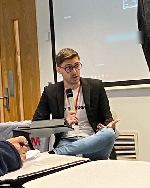 Albert C. Cano speaking on a conference panel, seen from the audience